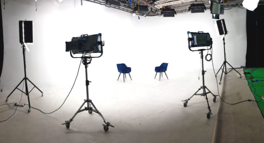 White infinity cove studio with two chairs and professional LED panel lights set up for a high-key interview video production