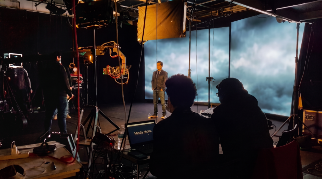 Virtual production studio with LED video walls, camera equipment and a production crew during a live shoot.